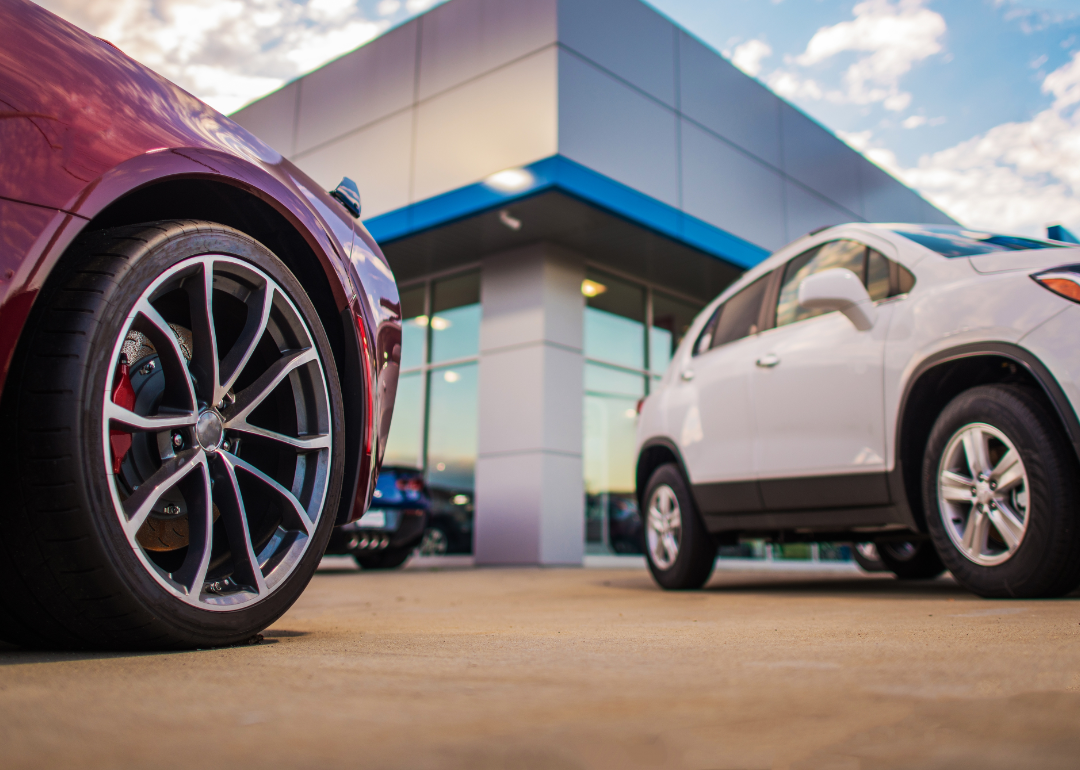 Two new cars parked outside an auto dealership.