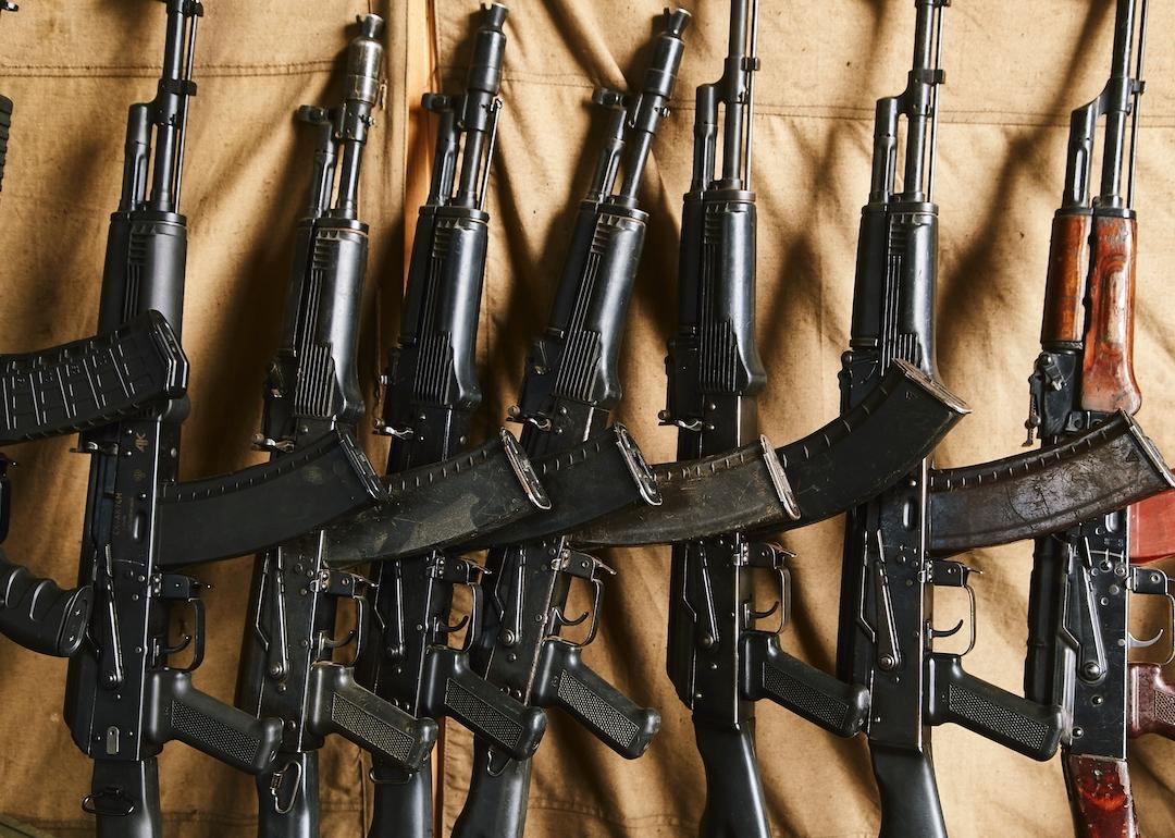 AK 47 assault rifles stand along the wall against a tarp.