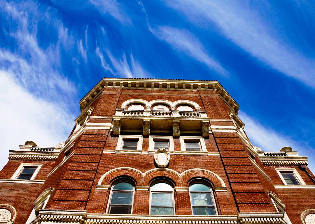Exterior view of an ornate, red brick college building against a blue sky.