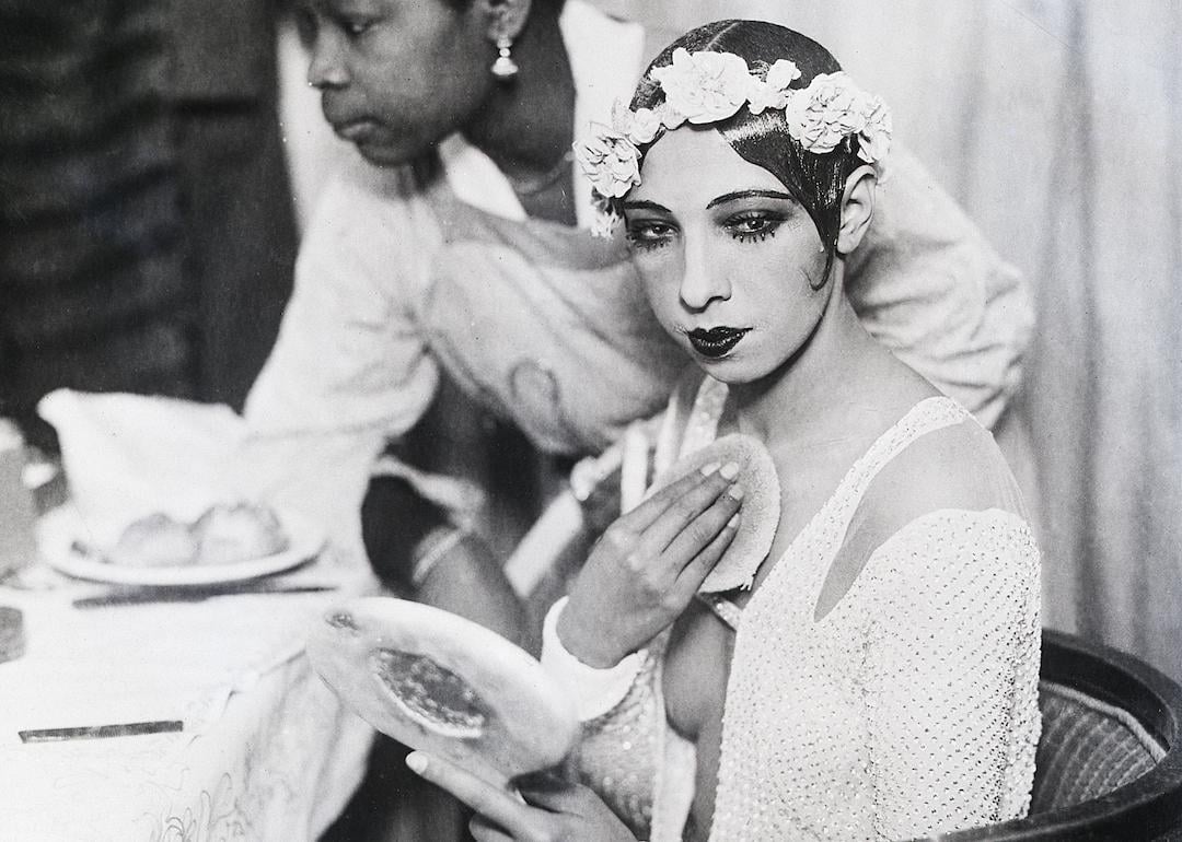 Josephine Baker putting on makeup while looking into a mirror in her dressing room in Vienna, Austria, in 1928.