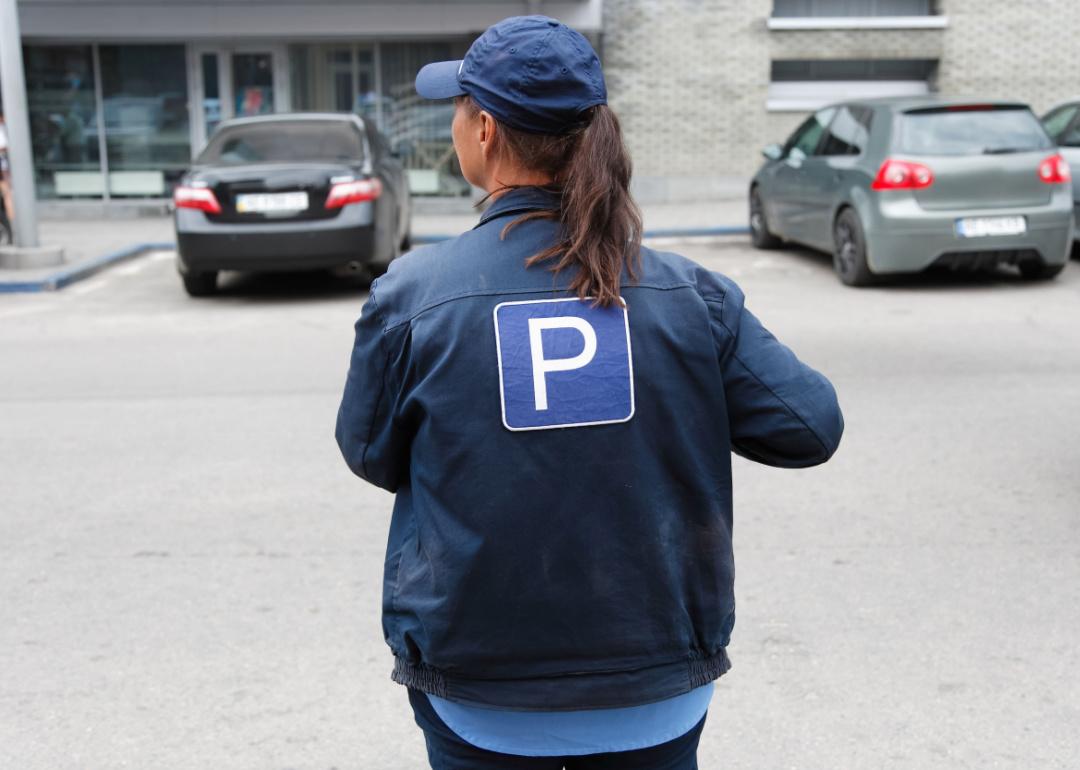 A parking attendant photographed from behind in a baseball cap and the letter 'P' on their jacket.