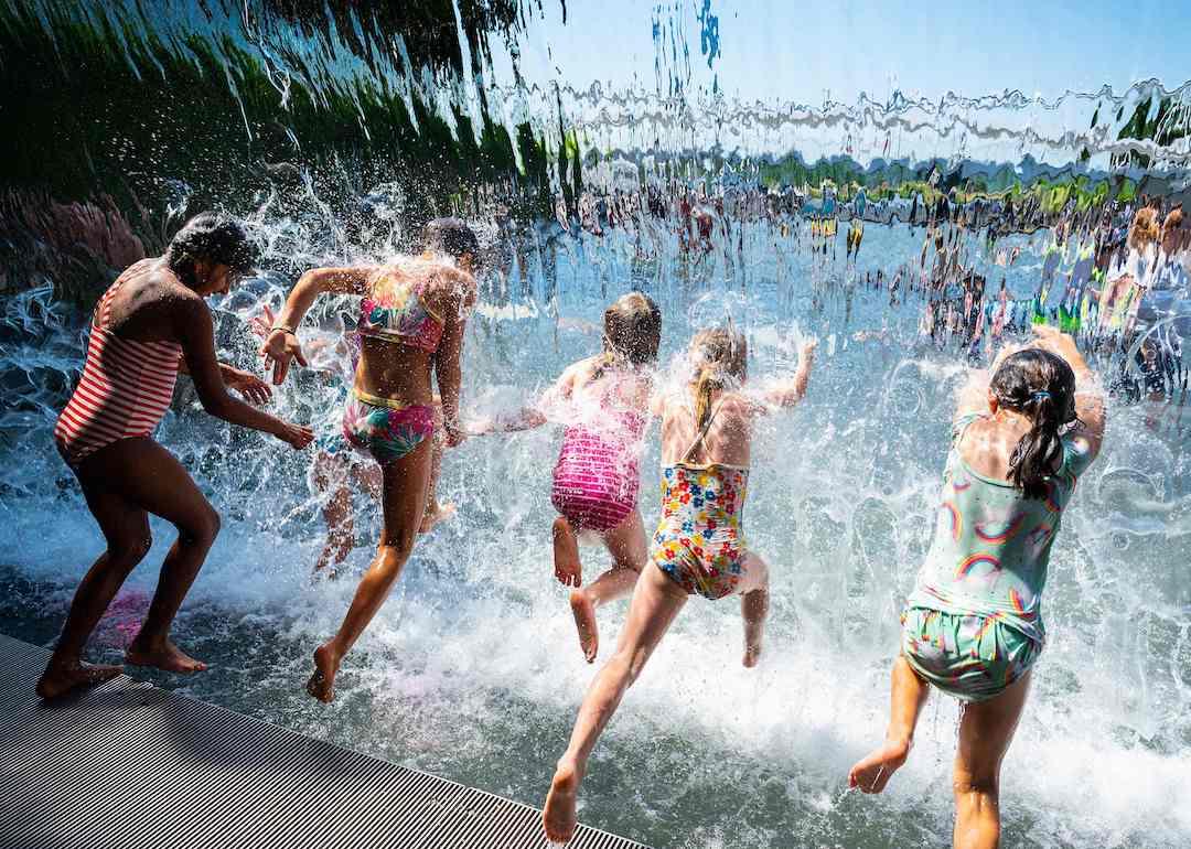 Kids splash through a waterfall at a park in Washington, DC, on June 28, 2021, as a heatwave moves over much of the United States.