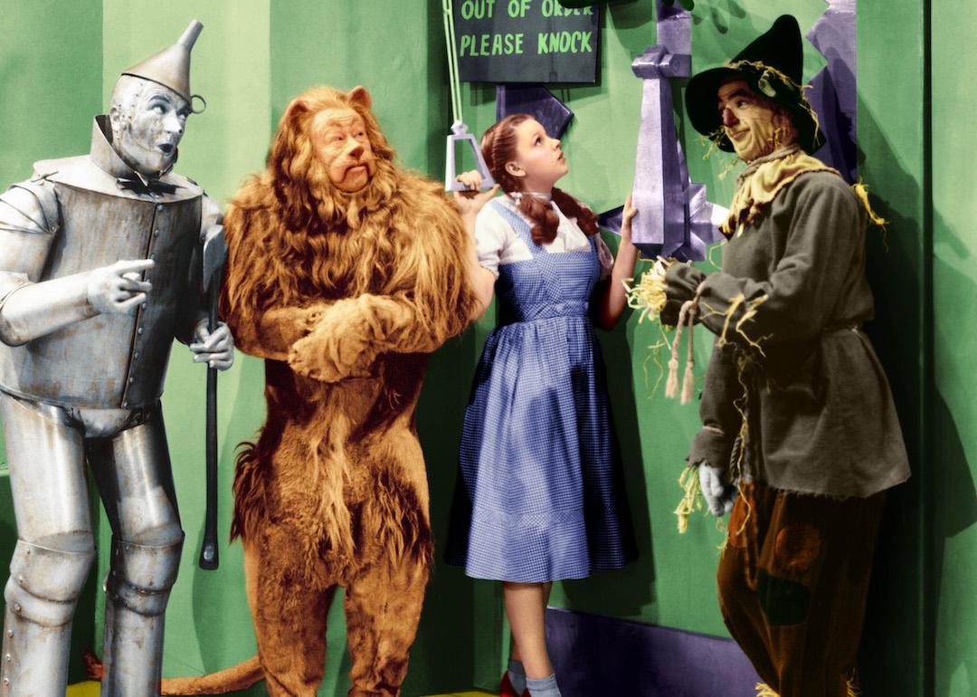 Jack Haley as the Tin Man, Bert Lahr as the Cowardly Lion, Judy Garland as Dorothy, and Ray Bolger as the Scarecrow in 'The Wizard of Oz,' based on the book 'The Wonderful Wizard of Oz.'