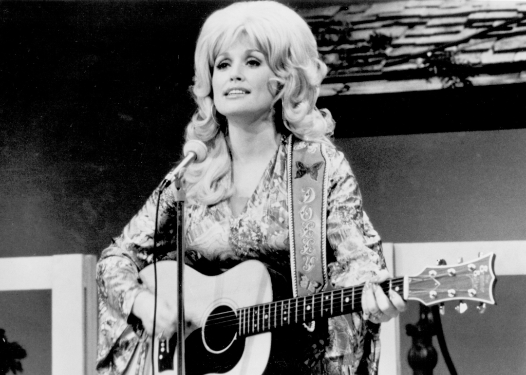 Country singer Dolly Parton performs onstage with an acoustic guitar in circa 1974.