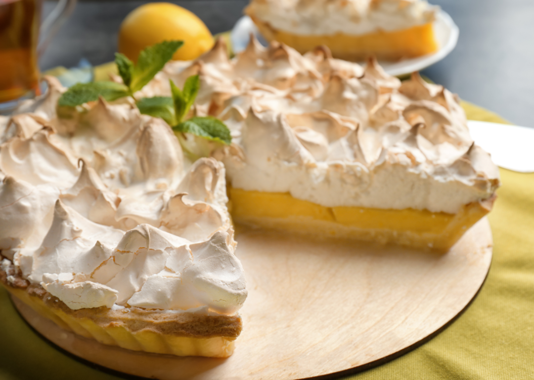 Lemon meringue pie on a wooden serving piece.
