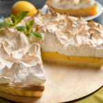 Lemon meringue pie on a wooden serving piece.