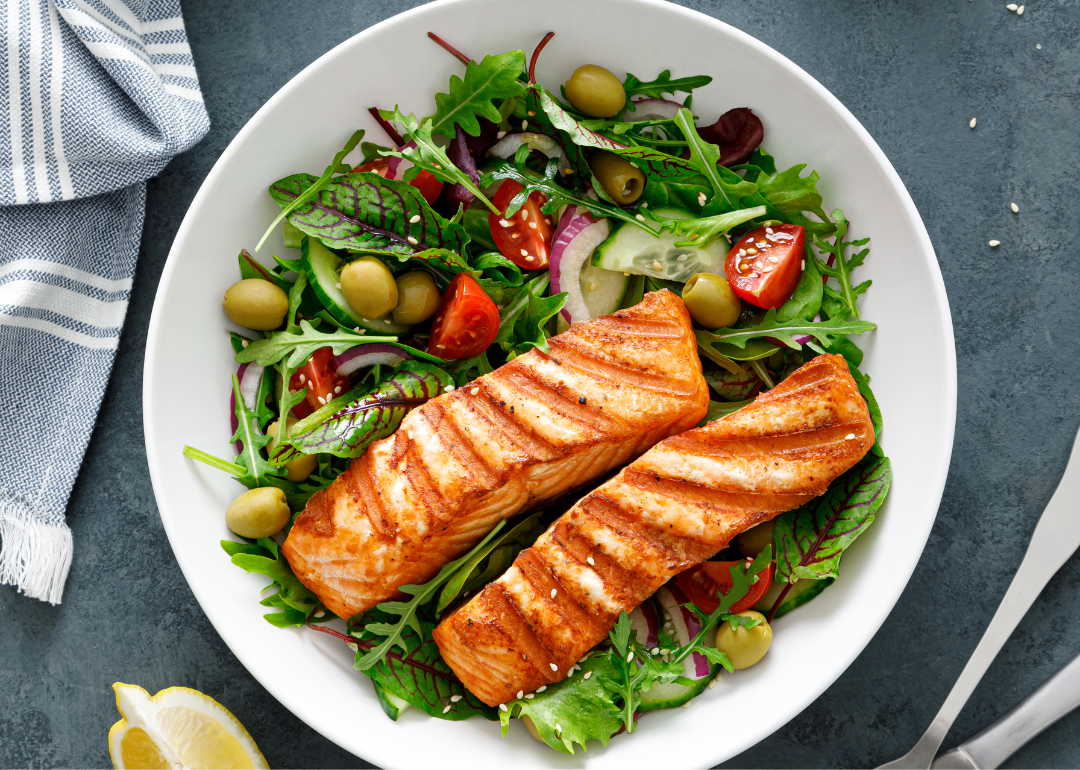Mediterranean salad with salmon in a white bowl on a slate table.