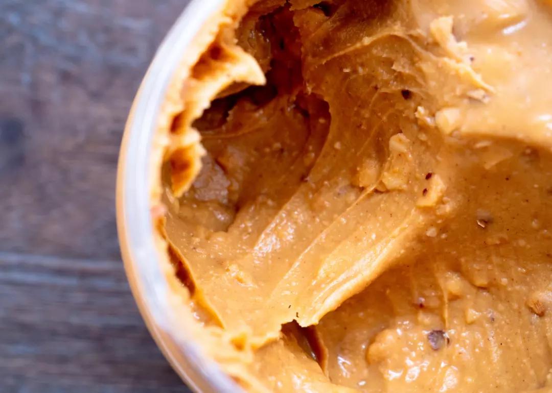 Closeup of an open jar of crunchy peanut butter.