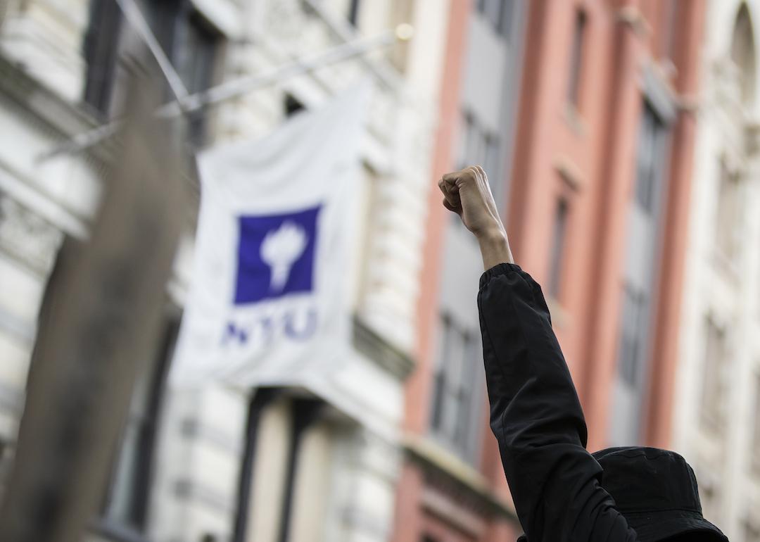 A protester holds up a raised fist with the NYU banner behind them as the procession of protesters made their way to Washington Square Park after the killing of George Floyd.