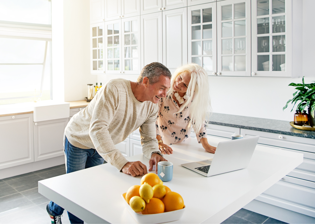 Retired couple planning retirement over kitchen island.