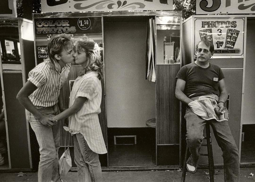 A young couple kisses in front of a photo booth at the Alameda County Fair, in Pleasanton, California, in 1986.