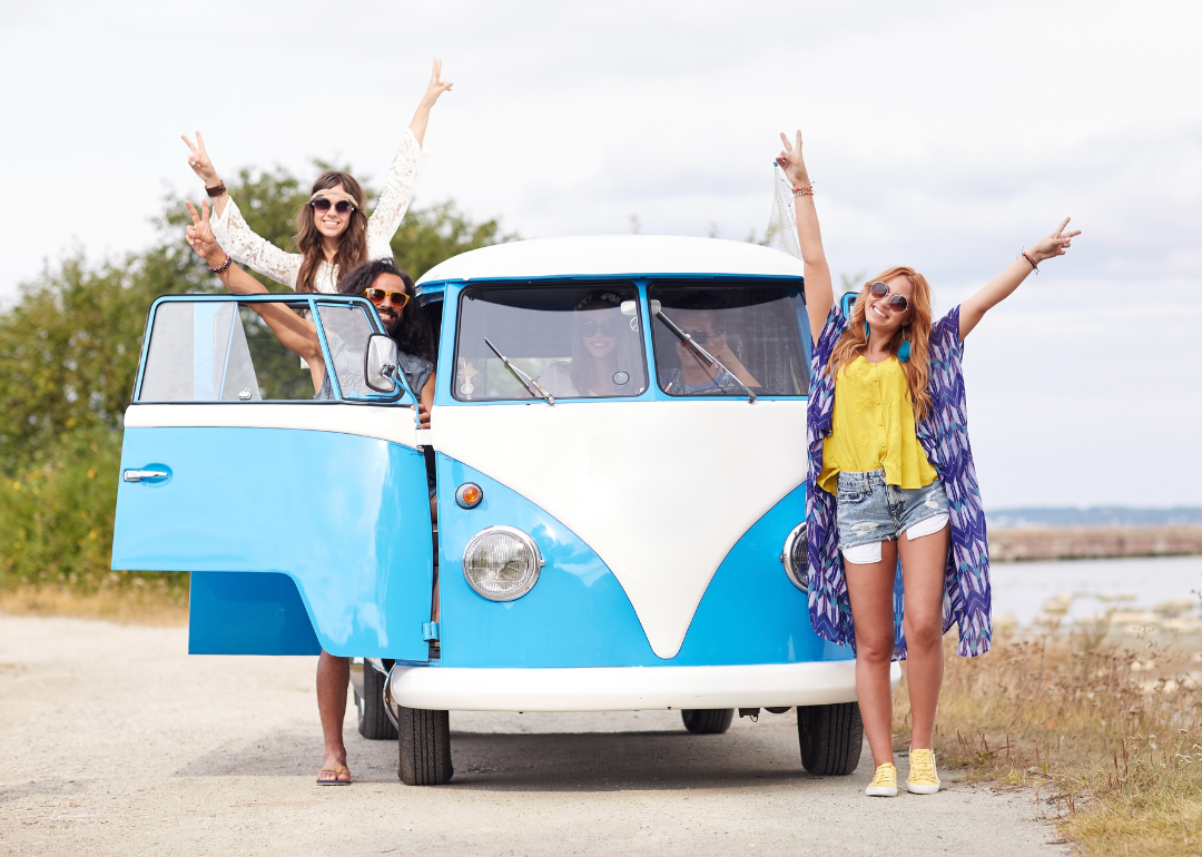 A diverse group of friends posing near hippie van.