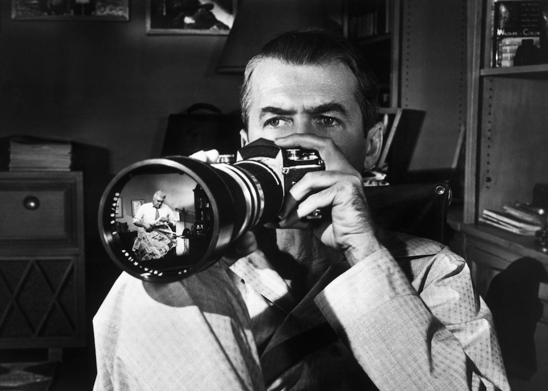 James Stewart watches Raymond Burr through a camera lens in Alfred Hitchcock's 1954 thriller 'Rear Window.'