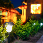 A solar powered light in a landscaped backyard at night.