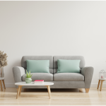 A gray sofa with green pillows with small wood end tables and coffee table