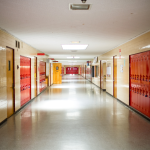 Empty school hallway with red lockers along the walls