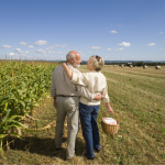 Senior couple standing next to a cornfield embracing and smiling at each other