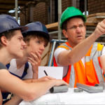 Two adolescent boys are fully focused on the level being held by their instructor. 