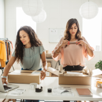 Two women at counter wrapping packages in a small business setting