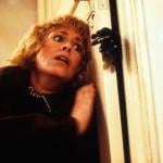 Actor Catherine Hicks hiding behind door in a scene from the film 'Child's Play.'