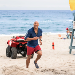Dwayne Johnson running on a beach in a scene from "Baywatch" (2017)