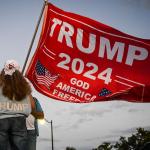 A supporter of former U.S. President Donald Trump holds a "Trump 2024" flag while protesting near the Mar-a-Lago Club in Palm Beach, Florida, on March 30, 2023. 