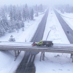 Truck plows a snow-covered road crossing the interstate highway in wintry United States