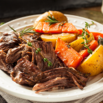 A loaded plate of homemade slow cooker pot roast with carrots and potatoes