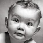 1950s baby with big light-colored eyes staring at the camera.