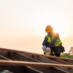 Construction worker installing wooden roof structure.