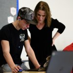 Teacher helping student on laptop