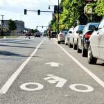 low angle view of road with bike lane, parking and drivers  