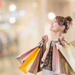 A young woman holding holiday shopping bags and smiling