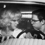 Actors Candy Clark and Charles Martin Smith in a car looking at each other in a scene from the 1973 film 'American Graffiti.'