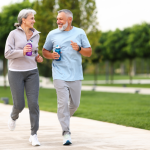 Senior couple smiling at each other while jogging through a city park