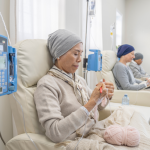 People sitting in chairs while receiving chemotherapy treatment.