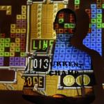 tetris game projected on the wall with player posing in the dark