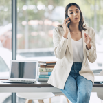 business woman on the phone with business books on desk in background