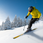 A skier in bright yellow jacket skiing down a slope.