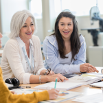 older teacher meets with 3 students sitting at a table