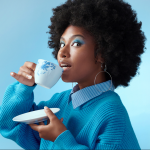 A Black woman with a teacup against a bright blue background.