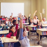 students raising hands in classroom