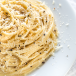 A plate of Cacio e Pepe pasta topped with freshly ground pepper