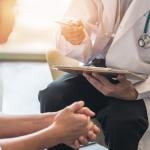 side profile of woman meeting with doctor holding clipboard 