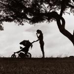 silhouette of mom standing with her hand on her face next to a stroller