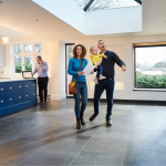 couple with young child views open house with realtor in the background