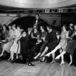 Female flappers kicking, dancing, and having fun while musicians perform during a Charleston dance contest at the Parody Club.
