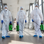 Specialists in hazmat suits cleaning and disinfecting a hallway