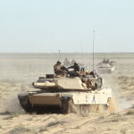 View of American M1A1 Abrams tanks as they cross the desert during the Gulf War, Iraq, 1991. 