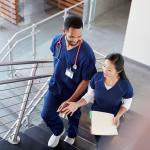 Two healthcare colleagues talking on the stairs at their hospital.